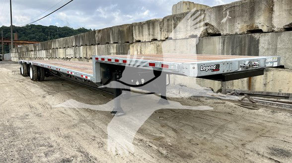 Manac steel drop deck trailer showing silver aluminum deck and Legend brand front corner.