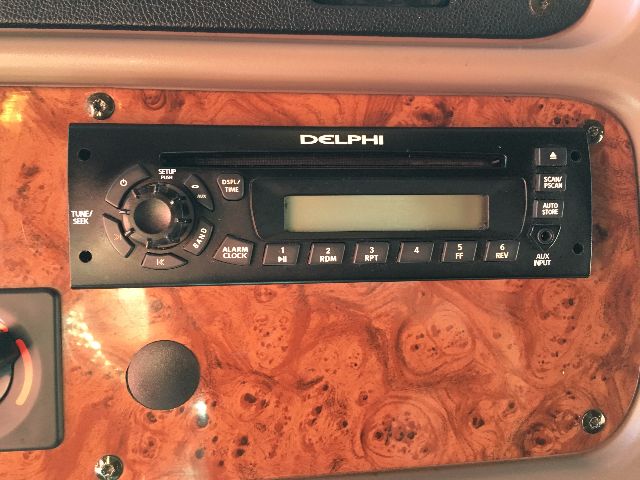 Delphi radio/entertainment unit mounted in a wood grain dashboard panel with control knobs and buttons.