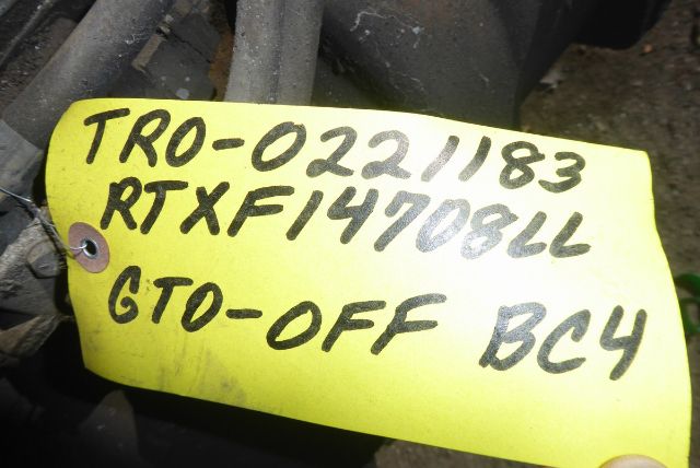 Tag with handwritten text 'TRO-021183 RTXF14708LL GTO-OFF BC4' attached to a yellow plastic tag on a transmission part.