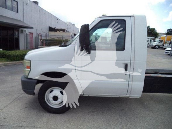 Ford E-450 cab with white paint and black bumper, side view showing front wheel and door, small window, and a stacked flatbed chassis. Overlay watermark of a bird graphic across the image.