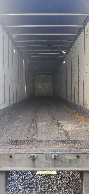 Empty Wabash dry van trailer interior seen from rear doors, long cargo area with metal walls and floor.