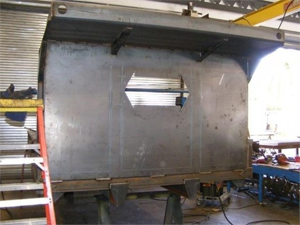 Dump body side panel of 14 ft Advanced Fabricators body with rectangular cutout and support braces.