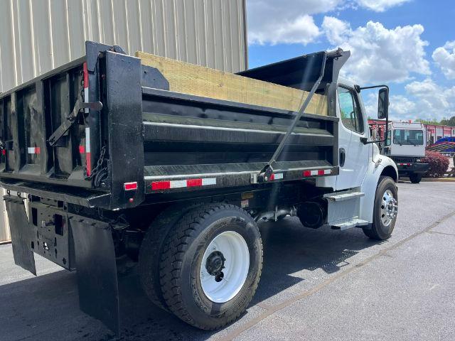 2018 Freightliner M2 106 dump truck with black dump bed, white cab, side view showing rear wheel and hydraulic components.