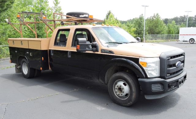 Ford F-350 utility truck with utility bed viewed from side, black lower body and tan cab, equipment racks on top.