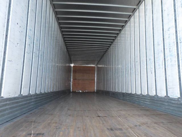 Inside of an empty 2009 Utility 4000DX composite trailer with metal interior walls and wooden floor.