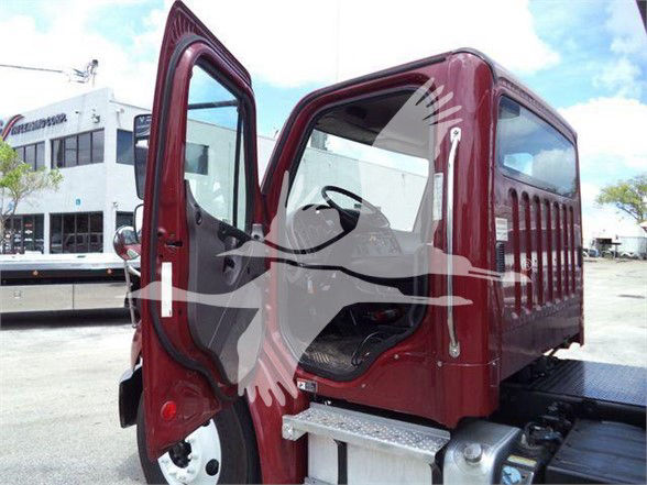 Truck cab interior visible with open doors on Freightliner Business Class M2 106, maroon exterior, steps and chassis, seating and steering wheel partially seen.
