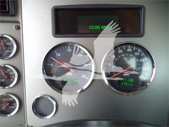 Dashboard gauges of a Kenworth truck showing tachometer RPM, speedometer, and digital display. Visible text includes '12:00 AM' on the digital screen and various numbers on gauges.