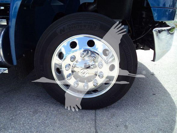 Truck wheel and chrome rim showing lug nuts and tire sidewall with visible tread; close-up of front wheel area on a blue truck.