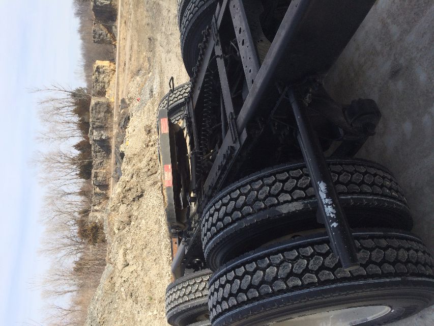 Dual rear wheels and chassis of a truck trailer with spare frame and suspension components visible.