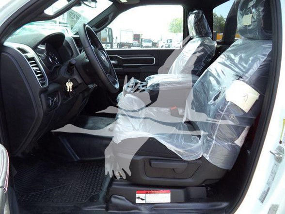 Ram 5500 interior showing front driver's seat and passenger seat covered in plastic, steering wheel, dashboard, and plastic-wrapped seats.