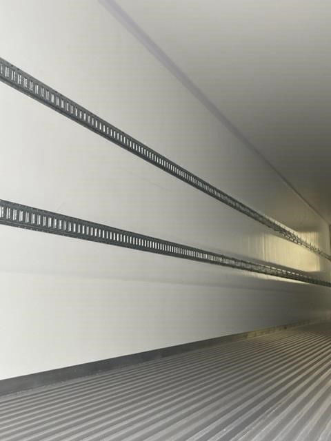 Inside trailer wall showing two horizontal slotted metal rails for racking along the length of the cargo area.