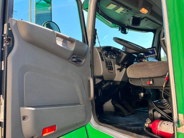 Truck cab interior of a 2015 Peterbilt 348 with the door open, showing the driver's seat, steering wheel, dashboard, and floor pedals.