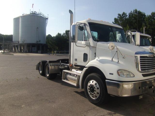 White Freightliner Columbia tractor cab showing front and side with chrome bumper and exhaust stack.