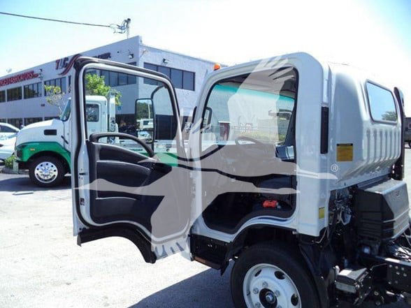 Isuzu NPR HD truck cab open showing interior; white cab with compact chassis and exposed engine area at rear; dealership lot in background.