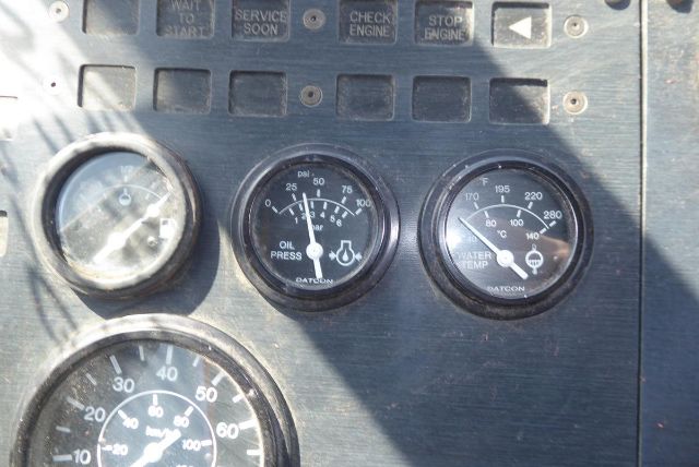 Dashboard gauges on a Kalmar yard truck showing oil pressure gauge and water temperature gauge with other dials, metal panel with worn labels.