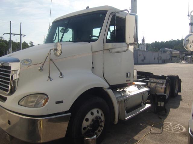 Tractor unit cab of a Freightliner Columbia semi-truck showing front and side view with large chrome fuel tanks and dual rear axles.
