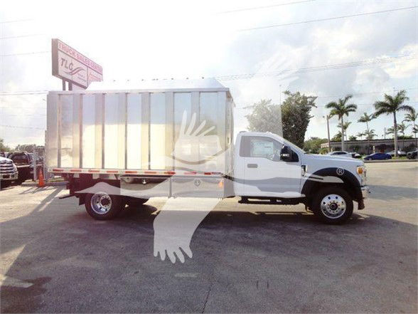 Ford F-600 truck chassis with a large metal dump bed in a lot.