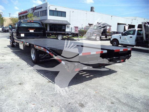 Truck bed tow-equipped flatbed visible with rear ramps and reflective tape.