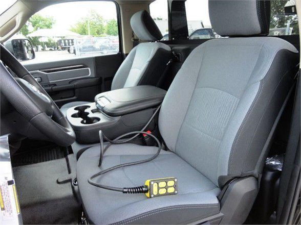Interior of a 2024 Ram 4500 HD SLT front seats with center console and steering wheel visible; charging cable plugged into a connector on the driver's seat.
