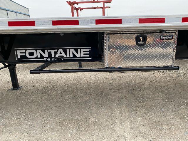 Flatbed trailer side with Fontaine Infinity branding and diamond-plate toolbox, undercarriage with a black step rail.