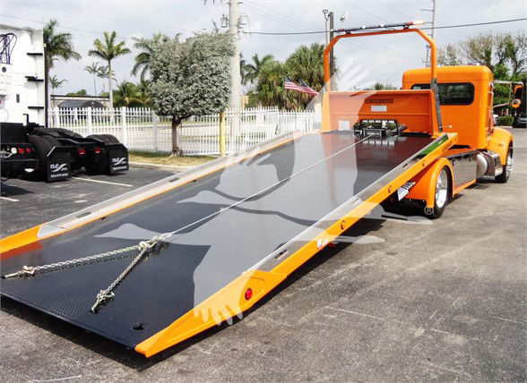 Peterbilt 337 tow truck with a long inclined flatbed in orange and gray colors.