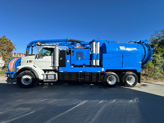 Sterling L7500 vacuum truck with white cab and blue tank showing industrial hoses on side and Vac-Con branding