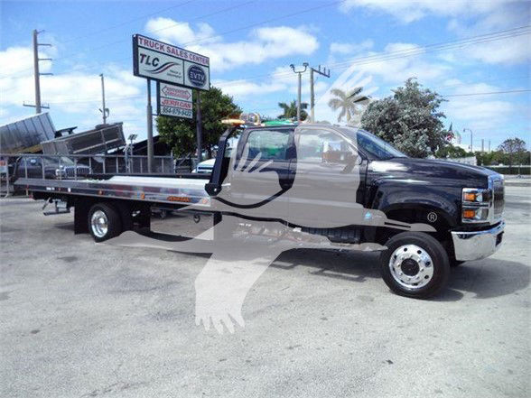 Truck showing a black 2023 International CV tow truck with a long flatbed in a dealership lot.