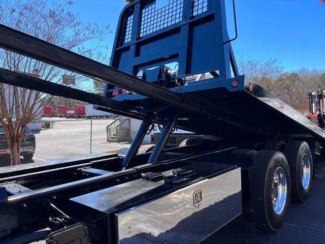 Peterbilt 348 rollback truck chassis showing wheel tires and flatbed with steel rails and support beams.