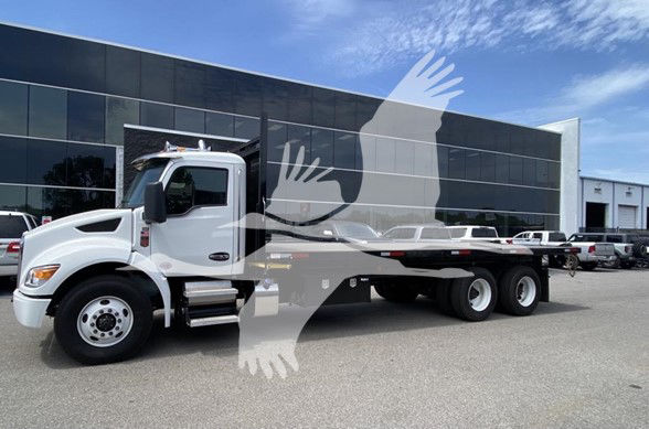 Kenworth T480 flatbed truck in white with long wheelbase and multiple axles parked outside a building.