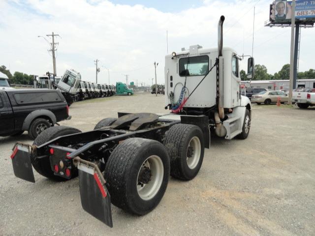 Truck chassis and cab of a Freightliner Columbia tractor seen from rear-left, with fifth-wheel and dual rear axles, exhaust stacks, and fuel tanks visible.