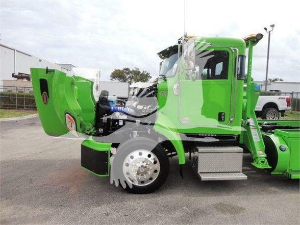 Peterbilt 337 tow tractor with green cab and wheel chrome hub showing engine bay components and hydraulic system.