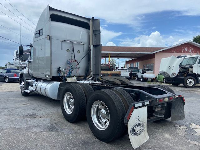 2010 Mack CXU613 conventional sleeper truck chassis rear view showing dual rear axles and exposed wiring on sleeper cab with white paint.
