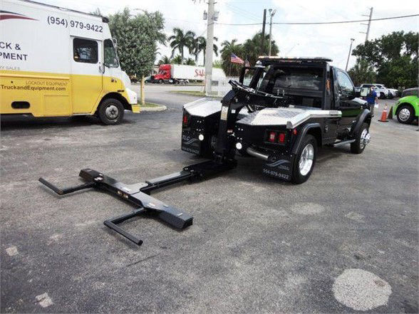 Ram 4500 HD SLT tow truck with wheel lift and hitch system in a lot.