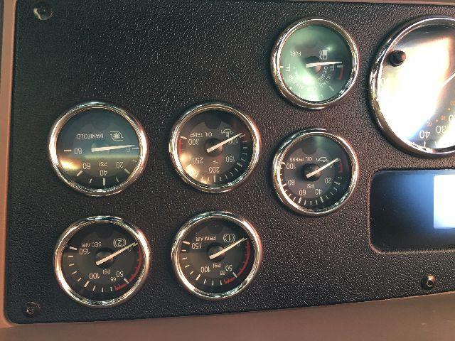 Peterbilt truck dashboard gauges cluster showing multiple round gauges with white needles and chrome rims.