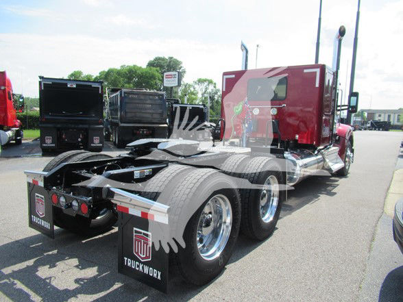 Kenworth W990 tractor from rear quarter showing dual rear axles and red sleeper cab. Mudflaps display 'TRUCKWORX' logo. Visible text includes 'TRUCKWORX' on mudflaps and trailer hitch area.