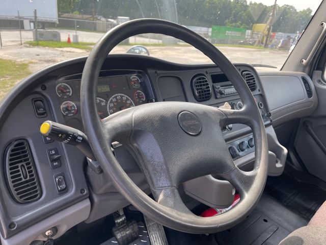 Freightliner M2 truck interior showing steering wheel, dashboard gauges, and center console.