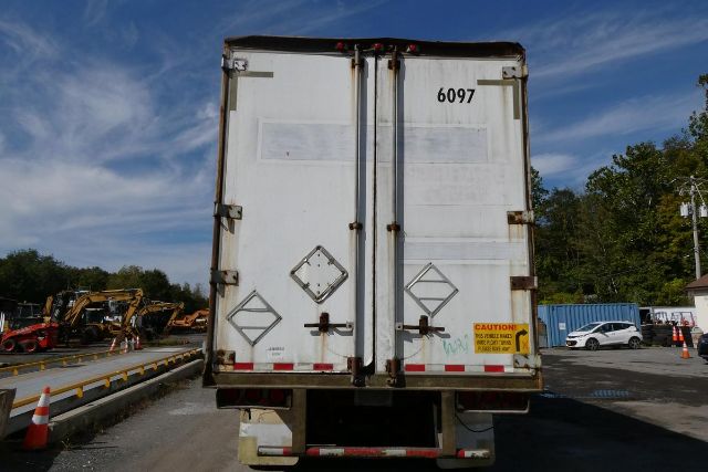 Rear view of a Fruehauf trailer with double doors, numbered 6097, and caution labels on the lower right door.