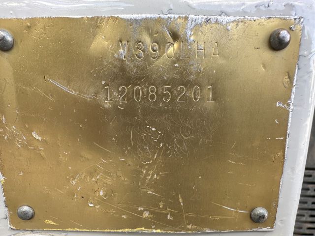 Brass identification plate with stamped serial numbers 189DHA and 12085201 mounted on a metallic surface with four screws.