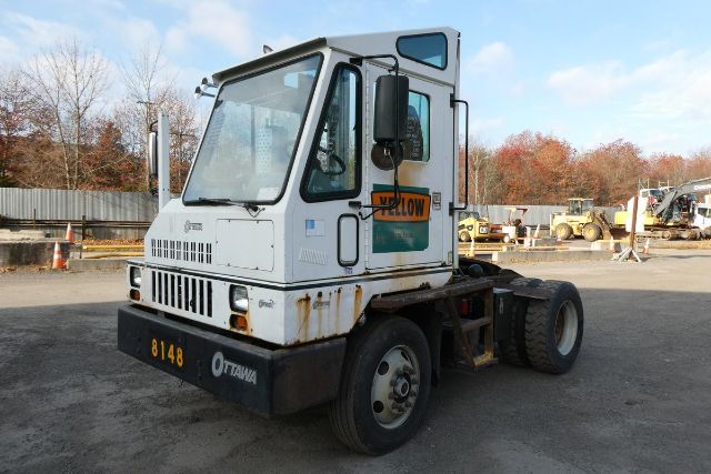Ottawa yard truck cab with white exterior and yellow ‘YELLOW’ sign on door, front grille, and damaged rust along lower body; single-axle tractor chassis in dirt lot.