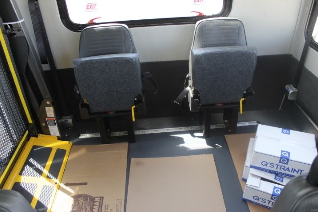 Ford E-450 shuttle bus interior showing two gray seats and box packaging along the floor.