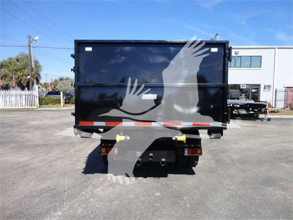 Isuzu NRR dump truck rear view showing black dump box and rear bumper with reflective orange-white stripes; tail lights visible; white silhouettes of hands overlay the image.