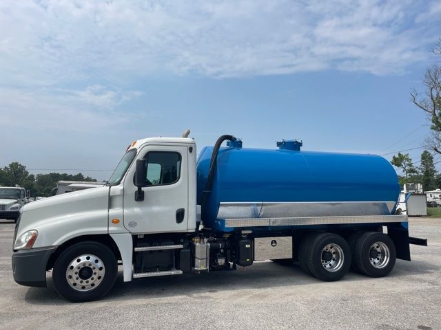 2013 Freightliner Cascadia vacuum/sewer truck with blue tank, white cab, side view showing rear dual axles and equipment compartments.