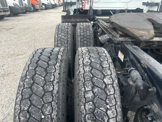 Tractor-trailer rear axle view showing dual rear tires and fifth-wheel area of a Freightliner Cascadia truck.