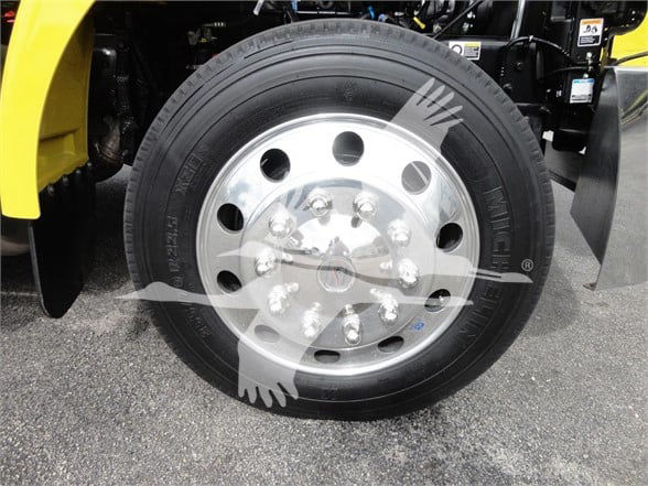 Peterbilt 337 front wheel showing large polished aluminum hub and tire. Visible text on tire: 'DUNLOP' (sidewall) and numbers around. The wheel has multiple lug nuts and a hubcap with Peterbilt logo.
