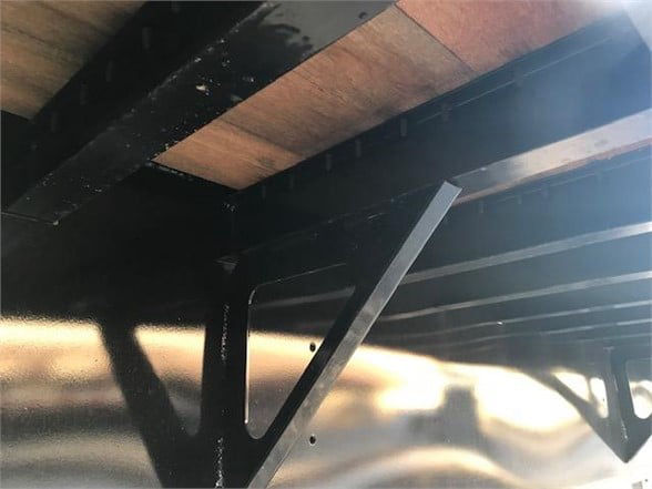 Flatbed trailer interior with metal frame and wooden decking showing structural beams.