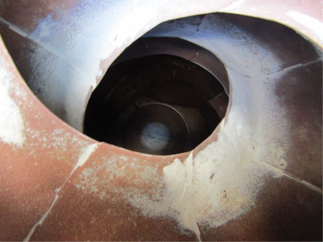 Open circular view into a cylindrical metal housing or exhaust-like opening with rust-colored surround.