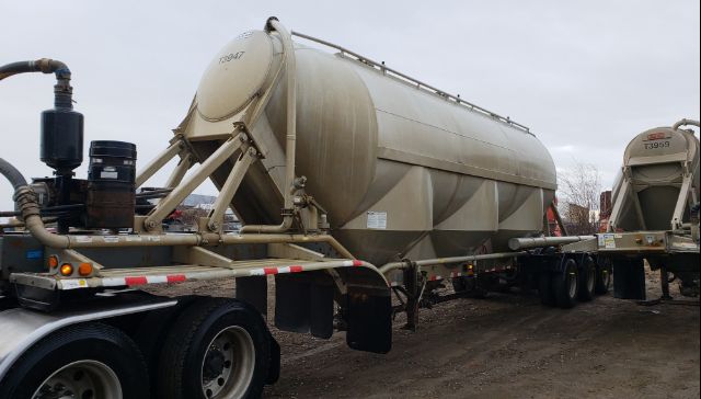 Tank trailer showing a large cylindrical stainless steel tank on a multi-axle trailer with supporting frame and wheels.