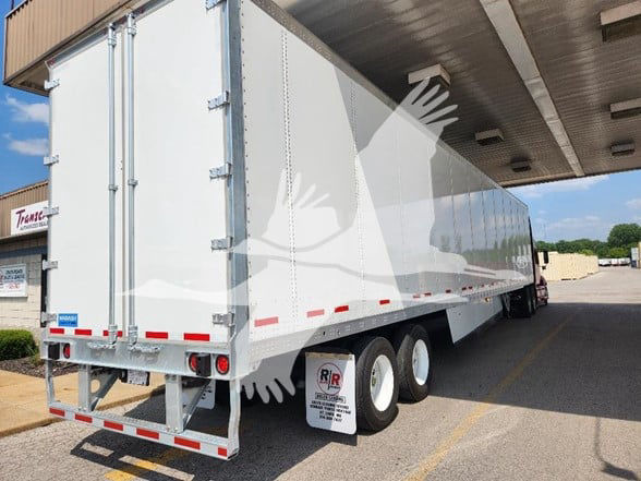 White Wabash trailer in a loading dock area with tandem axle group and rear doors, under a canopy.