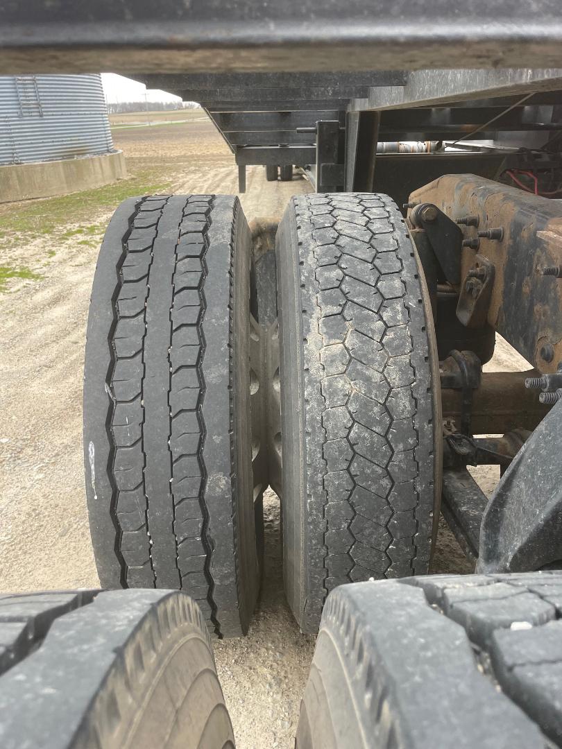 Two rear truck tires side-by-side with visible tread patterns under a Freightliner Cascadia 125 tractor trailer.