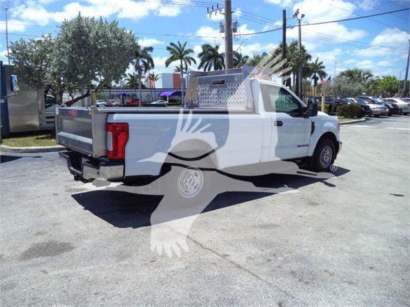 Ford F-250 pickup truck with utility bed and rack in a dealership lot.